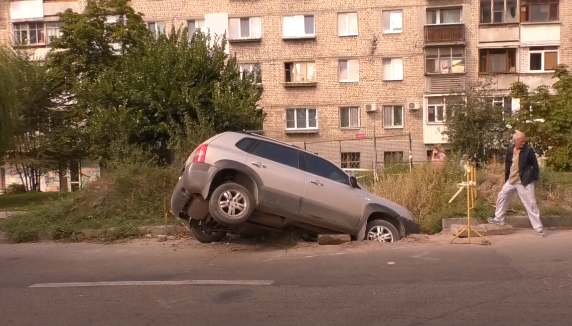 Не можуть витягнути цілий день: на вулиці Зерновій машина потрапила до ями (фото)