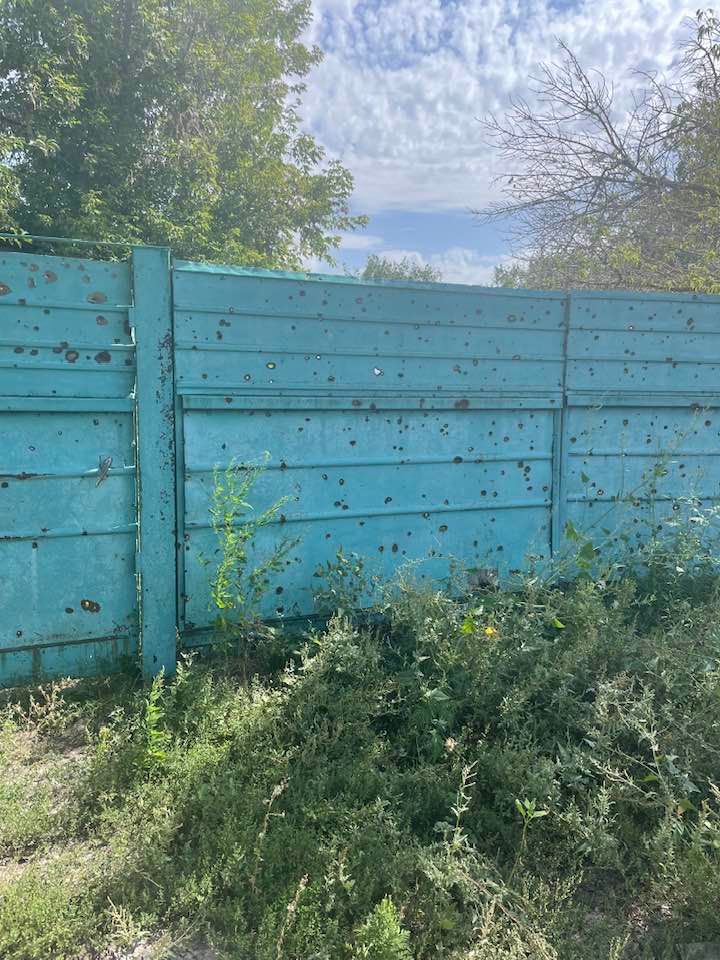 Забор в селе Изюмского района, посеченный осколками