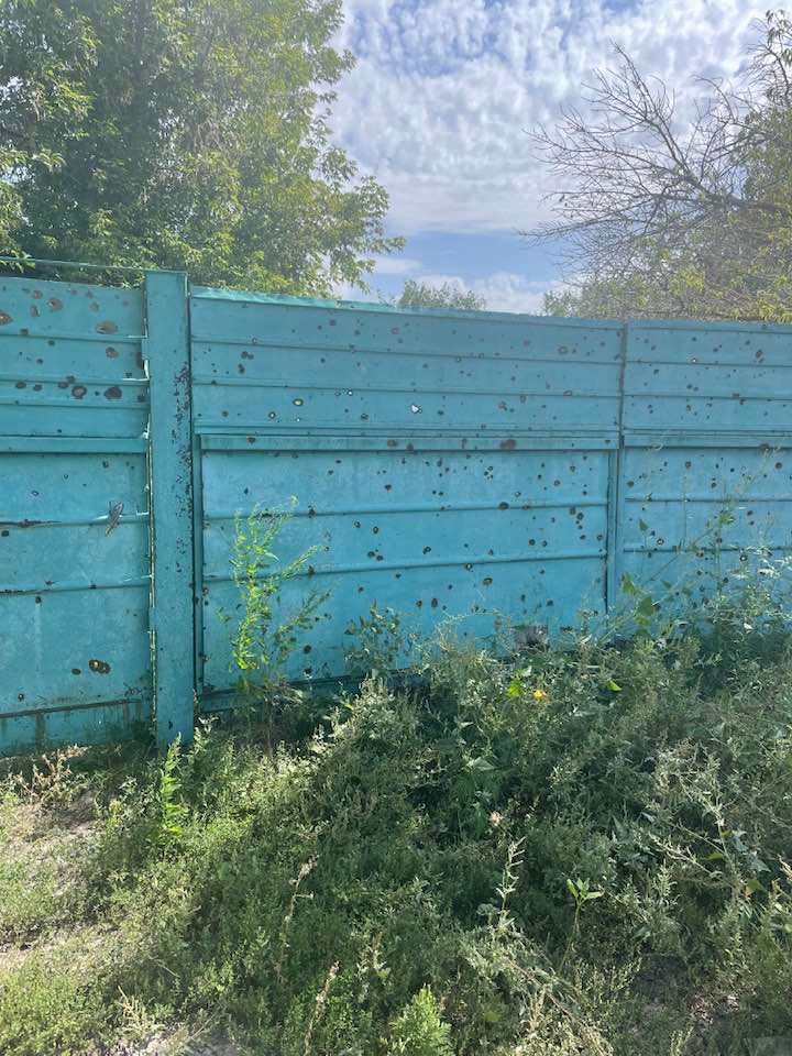 Забор в селе Изюмского района, посеченный осколками