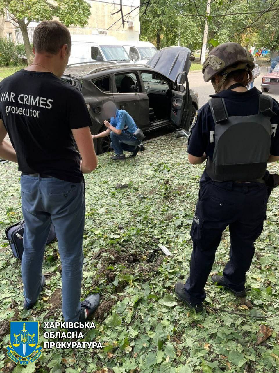 Прокуроры осматривают сгоревшую машину в Харькове после российского обстрела