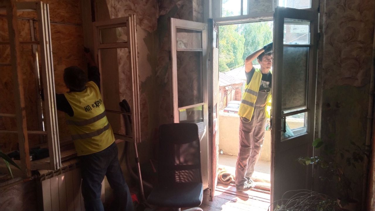Коммунальщики закрывают ДСП выбитые окна и двери в Харькове после обстрела 18 августа