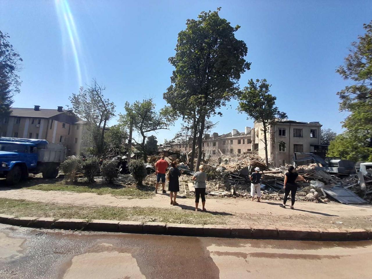 Люди возле руин общежития, разрушенного российским обстрелом в Харькове