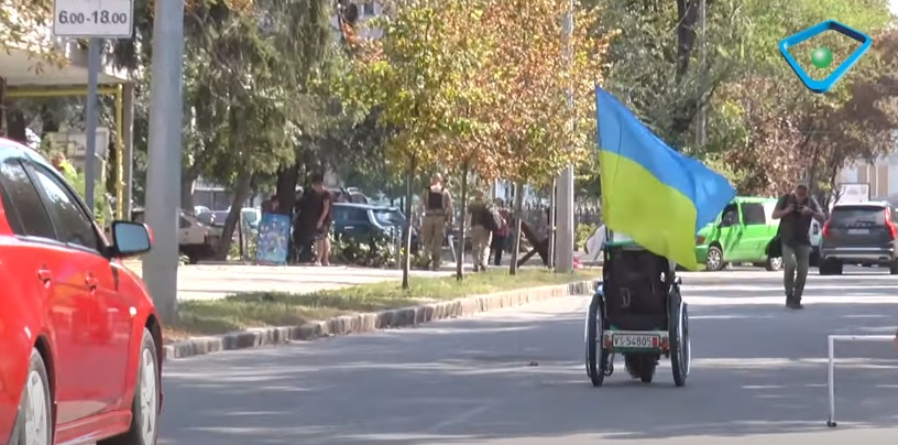 Розсікає Харковом на інвалідній колясці із українським прапором (сюжет)